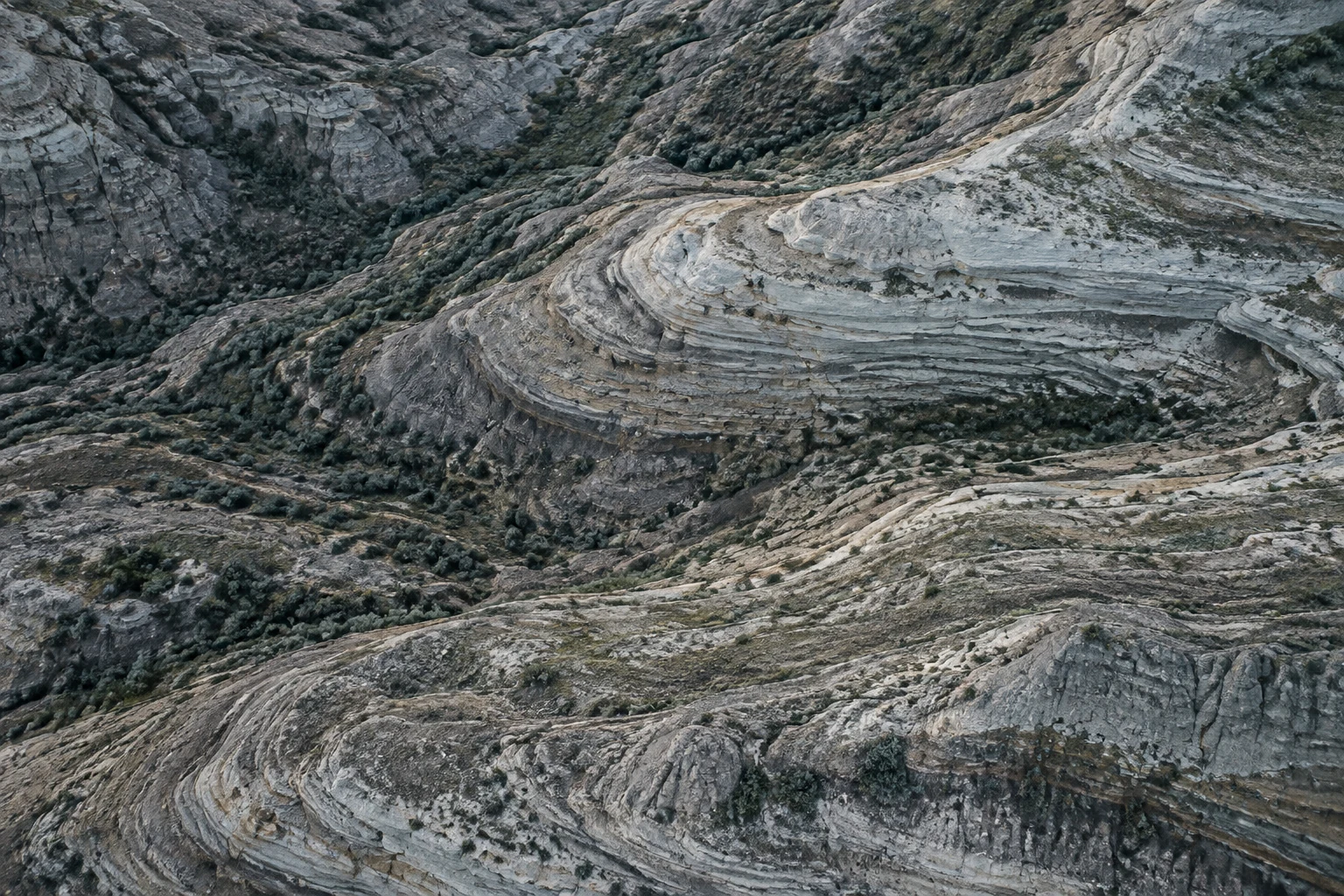 Layers of pale stone and green terrain seen from above.